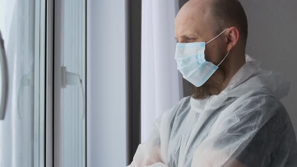 A Tired Doctor Stands at the Window in a Mask After Working with Fried Patients in Danger of alt