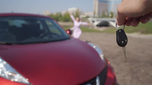 The Girl Snatches the Keys From the Man's Hands and Runs Happily Hugging a New Car alt