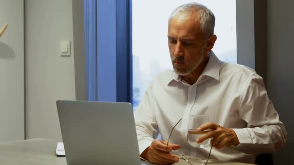 Businessman having a glass of water while using laptop 4k alt