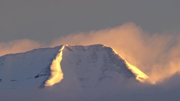 Clouds blowing over the top of snow covered Timpanogos Mountain alt