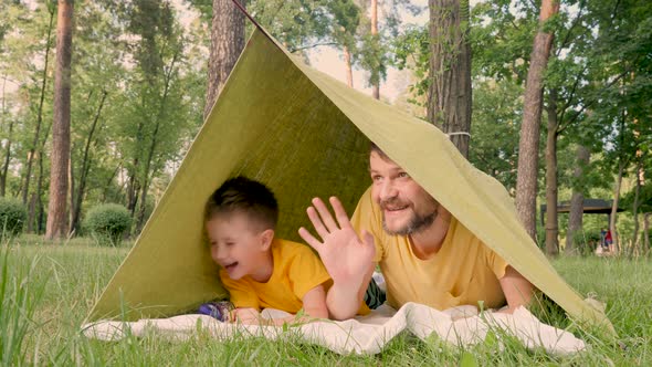 Father with Son Lying in Camp Tent. Two Travelers Having Fun in Tent. Traveling Close To Home