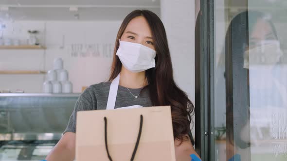 Asian waitress with face protective mask delivering takeaway coffee and food bags to customers