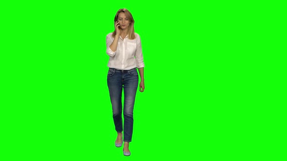 Blonde Woman Is Calmly Walking and Talking on the Mobile Phone on Green Screen. Chroma Key, Shot alt