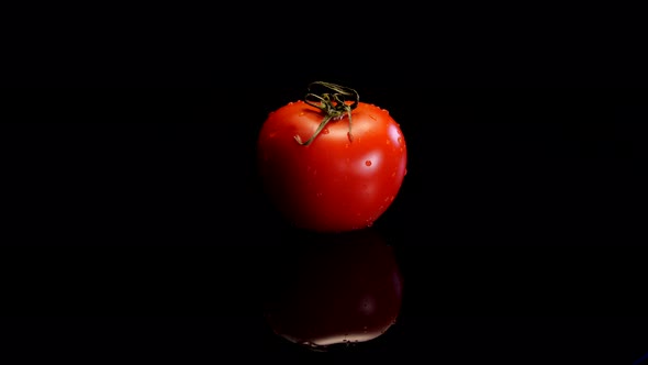 Red perfect tomato rotating on a black background. Fresh and firm tomato in 4K