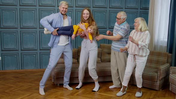 Family Members of Different Generations Having Fun Listening Music Dancing Crazy in Room at Home alt