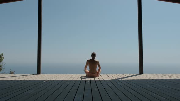Naked Man in Pink Shorts Sits at the Edge of the World and Looks Into the Distance. In the alt