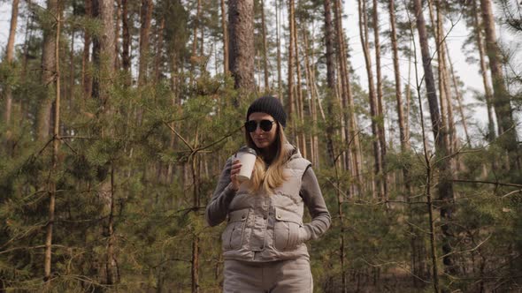 Steadycam Shot. Woman Drink Coffee in the Pine Forest