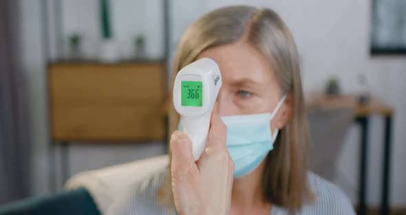 Hand which Holding Infrared Thermometer and Showing 36,6 on Screen After Measuring Temperature alt