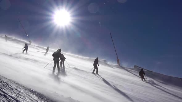 Skiers on a Ski Slope With a Blizzard on a Sunny Day