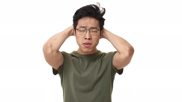Portrait of Anxious Asian Man 20s Wearing Glasses Grabbing Head in Confusion While Expressing Stress alt