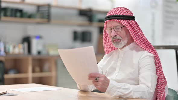 Senior Old Arab Businessman Having Success on Documents in Caf� alt