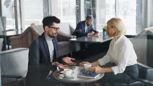Successful Business People Mature Man and Woman Talking and Laughing in Cafe alt