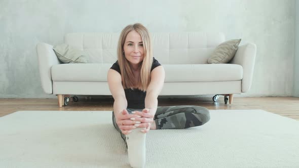Attractive woman with prosthetic leg Sits on floor and stretches her leg muscles