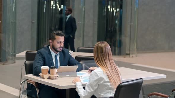 Manager and his partner sitting on the table in cafe and discussing diagram