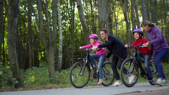 Young guy and girl teach children to ride a bike in the Park.  Two little girls riding