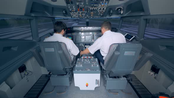 Two Pilots Check Equipment in a Cockpit alt