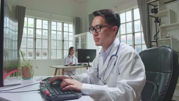 Asian Man Doctor Is Using Desktop Computer In Workplace. Medical Concept alt