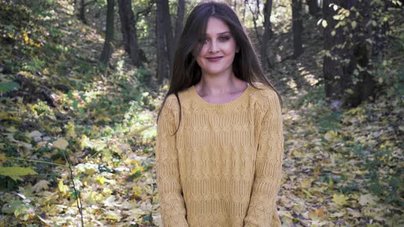 A Girl Walking in an Autumn Park with Yellow Fallen Leaves alt