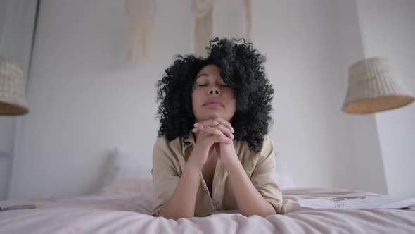 Portrait of Young Focused Woman Lying on Bed Looking at Camera Shaking Head Yes alt