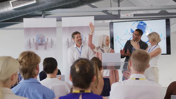 Female speaker and applauding audience and colleagues at a business conference alt