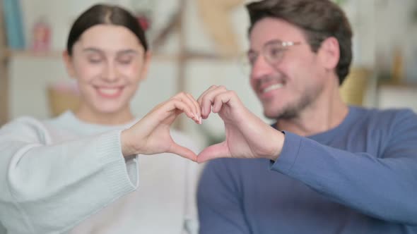 Portrait of Happy Hispanic Couple Holding Hands in Heart Shape alt