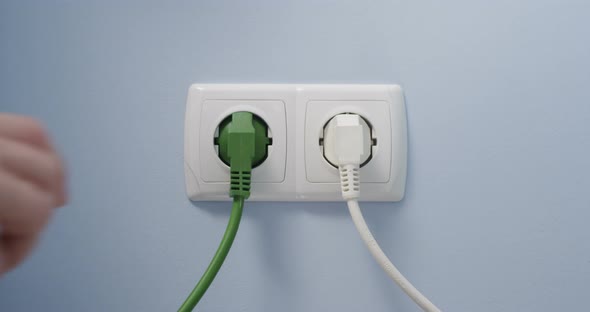 Hand Plugging Green Power Cord In Socket Concept Eco Green Energy Efficiency Ecology Sustainability alt
