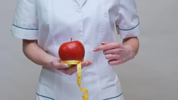 Nutritionist Doctor Healthy Lifestyle Concept - Holding Organic Red Apple and Measuring Tape alt