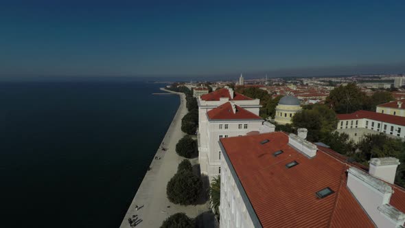 Aerial view of a waterfront with white buildings alt
