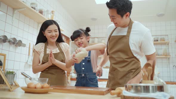 Asian happy family spending time in kitchen together, parent teaching young daughter bake bakery. alt