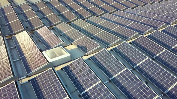 Aerial view of many photo voltaic solar panels mounted of industrial building roof. alt