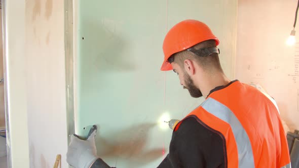 Male Contractor in Hardhat Installing Drywall During Renovation