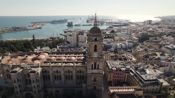 Aerial forward view of a side of cathedral with port in background. Malaga. Spain