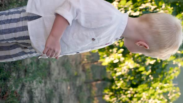 Child Boy Blond Stands at Sunset in the Vineyard and Looks alt