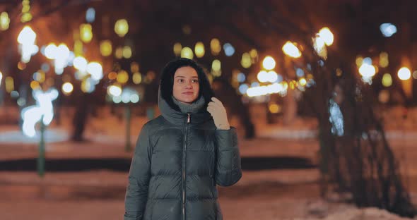 Young Pretty Woman is Walking in the Park in the Evening Lights are on