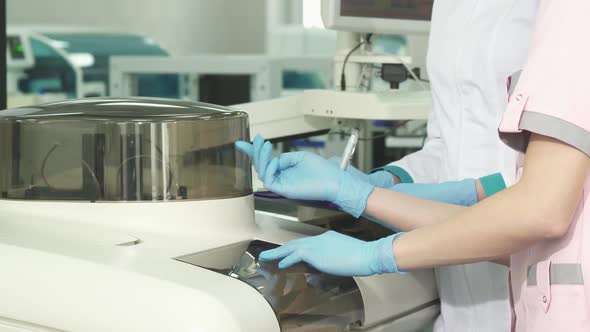 Cropped Shot of Tow Female Laboratory Technicians Examining Analysing Machine alt
