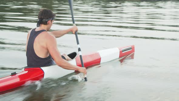 Young Strong Man Kayaking Fast