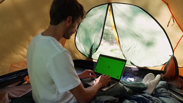 Freelance Working at a Laptop While Lying in a Tent Typing Text and Remote Work in Nature Man Works alt