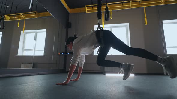 Athletic Woman is Practicing Modern Fitness System with TRX for Trainingher Body alt