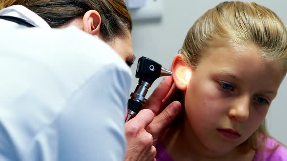 Female doctor examining patient ear with otoscope alt