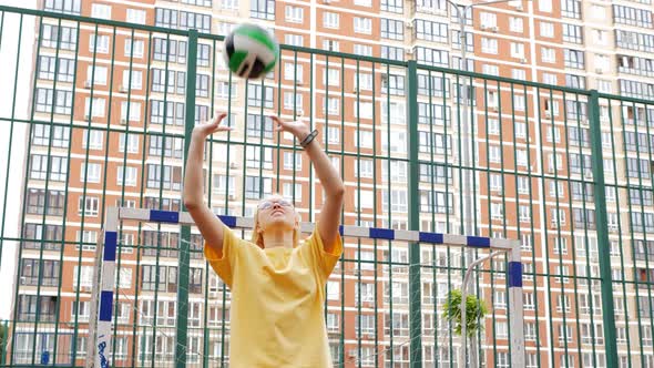 A Sportylooking Teenage Girl in a Yellow Tshirt and Yellow Shorts Trains with a Volleyball Ball on