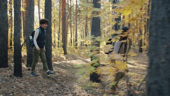 Caring Man Walking in Forest with Wife and Son Enjoying Backpacking on Autumn Day alt