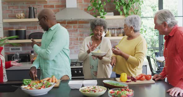 Group of happy diverse senior friends cooking together in kitchen alt