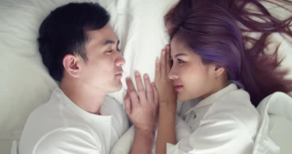 Happy Asian husband and pregnant wife spend time together in the bedroom in the morning.