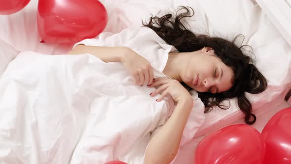 Brunette European Girl Sleeping on Bed with Red Heart Shape Balloons alt