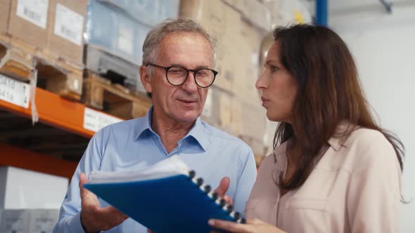 Mature woman and man analyzing documents in the warehouse. Shot with RED helium camera in 8K. alt