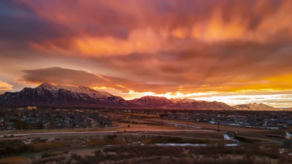 Sunrise casts orange rays of sun into the colorful sky and cloudscape above the waking city and high alt