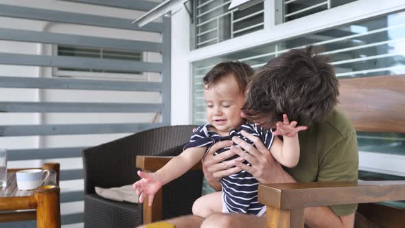 A Father with a Beautiful Son 810 Months Old are Sitting at Home on the Terrace Having Fun Together