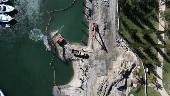 Large construction machinery working on a coastal project to develop a new boating marina and harbor alt