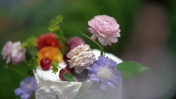 Beautiful cherry toppings and wildflower arrangement on top of a detailed white wedding cake alt