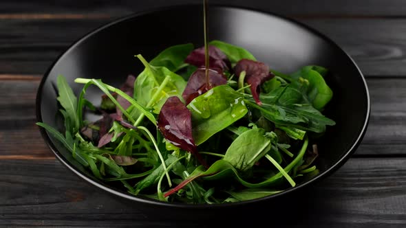 pour olive oil on fresh green salad with arugula, spinach. healthy lifestyle concept  alt